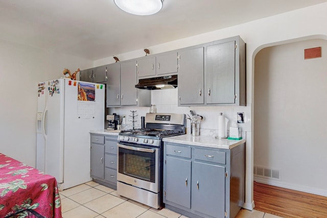 kitchen featuring gas range, gray cabinetry, and white refrigerator with ice dispenser