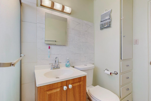 bathroom featuring tile walls, toilet, decorative backsplash, and vanity