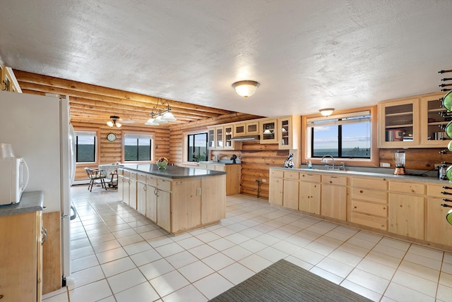 kitchen with a textured ceiling, a kitchen island, sink, hanging light fixtures, and log walls