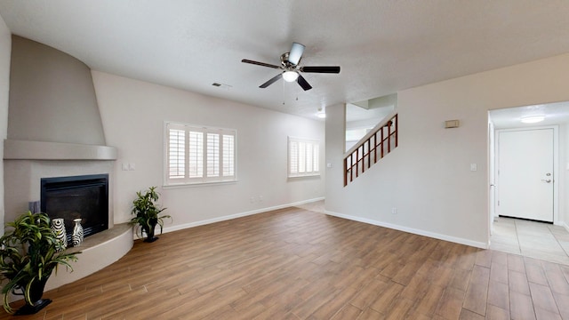 unfurnished living room with ceiling fan, light hardwood / wood-style flooring, and a fireplace