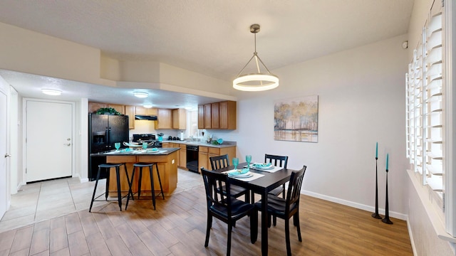 dining area with a textured ceiling and light hardwood / wood-style flooring