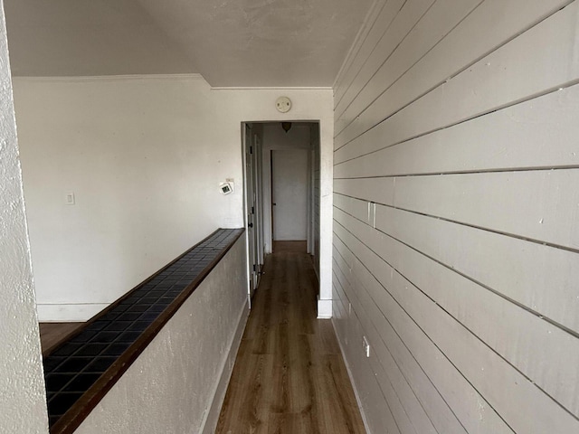 hallway with crown molding, wooden walls, and dark hardwood / wood-style floors