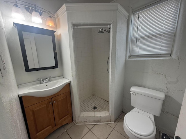 bathroom featuring tile patterned floors, vanity, toilet, and a tile shower