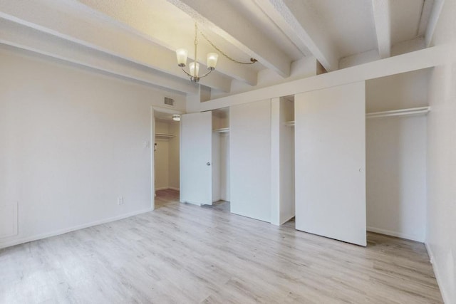 unfurnished bedroom with beamed ceiling, a chandelier, and light hardwood / wood-style floors