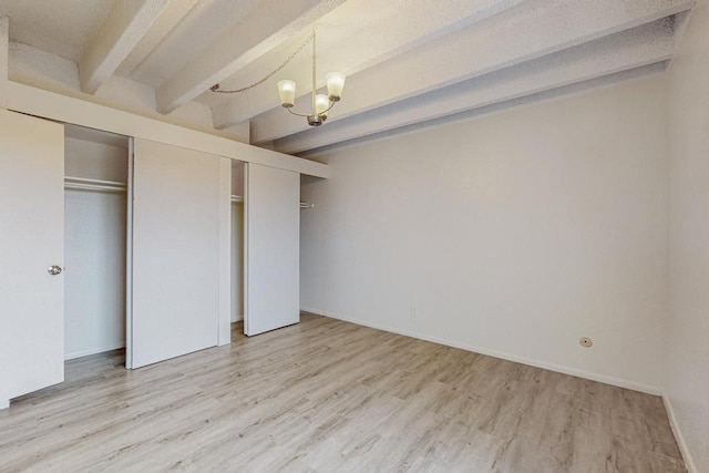 unfurnished bedroom with beamed ceiling, a chandelier, and light hardwood / wood-style flooring