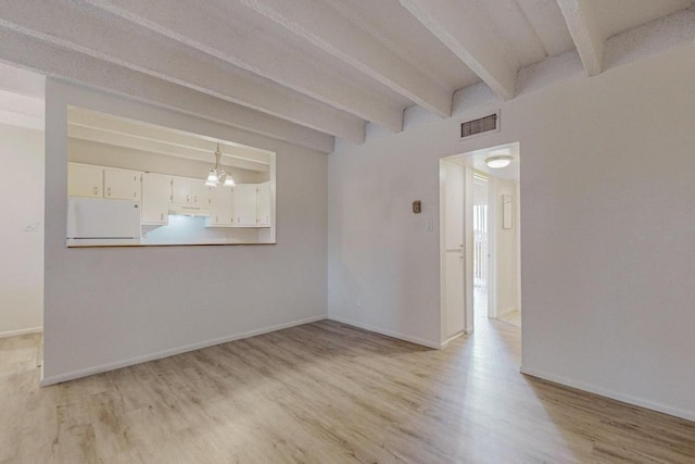 spare room with beamed ceiling, an inviting chandelier, and light hardwood / wood-style floors