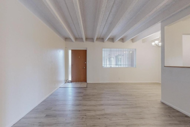 empty room with beam ceiling, light hardwood / wood-style floors, and a chandelier