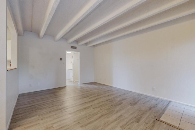 spare room featuring beam ceiling and light hardwood / wood-style flooring