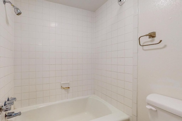 bathroom with tiled shower / bath combo and toilet