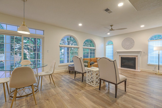 dining area featuring light wood-type flooring, visible vents, a glass covered fireplace, and recessed lighting