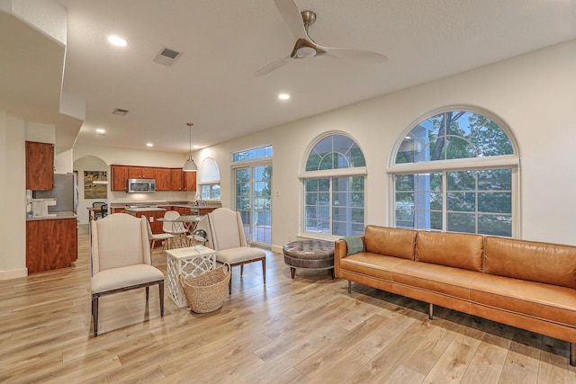 living room featuring arched walkways, recessed lighting, visible vents, light wood-style floors, and ceiling fan