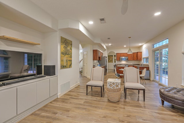 living room with arched walkways, visible vents, and light wood-style floors