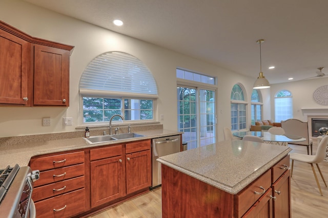 kitchen featuring a glass covered fireplace, open floor plan, stainless steel appliances, light wood-style floors, and a sink