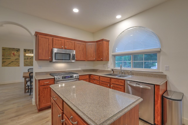 kitchen with light wood-style flooring, brown cabinets, stainless steel appliances, a sink, and recessed lighting