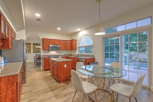 kitchen with light wood finished floors, visible vents, a center island, stainless steel appliances, and a sink