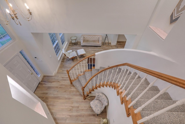 stairs featuring baseboards, wood finished floors, and an inviting chandelier