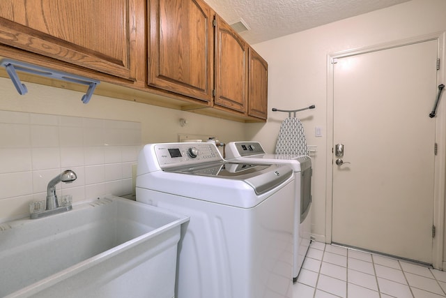 laundry room with a textured ceiling, a sink, visible vents, cabinet space, and washing machine and clothes dryer