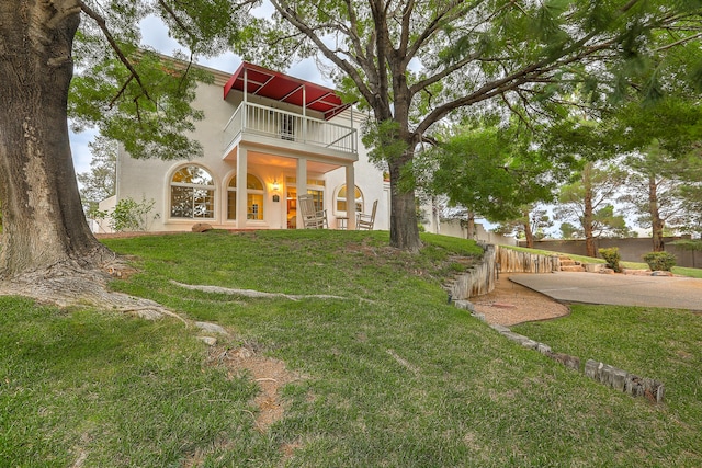 exterior space with a yard, a balcony, and stucco siding