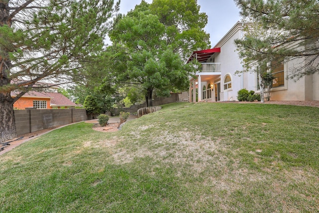 view of yard with a fenced backyard and a balcony