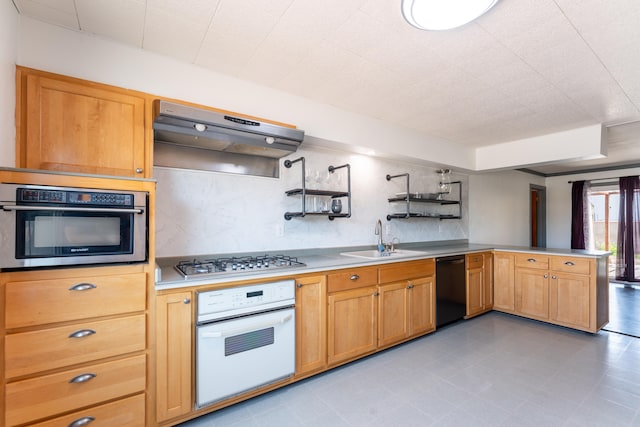 kitchen with backsplash, exhaust hood, kitchen peninsula, sink, and appliances with stainless steel finishes