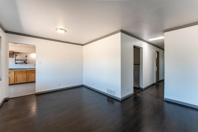 unfurnished room with crown molding, dark wood-type flooring, and a textured ceiling