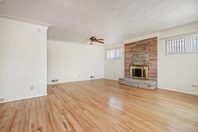 unfurnished living room featuring ceiling fan, a fireplace, crown molding, and light wood-type flooring