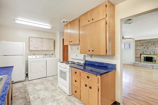 kitchen featuring separate washer and dryer, ceiling fan, a stone fireplace, and white appliances