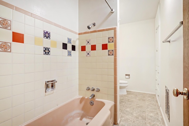 bathroom featuring toilet and tiled shower / bath