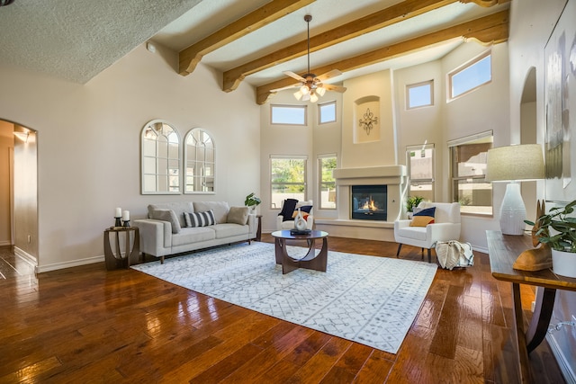 living room featuring a textured ceiling, hardwood / wood-style floors, ceiling fan, and beamed ceiling