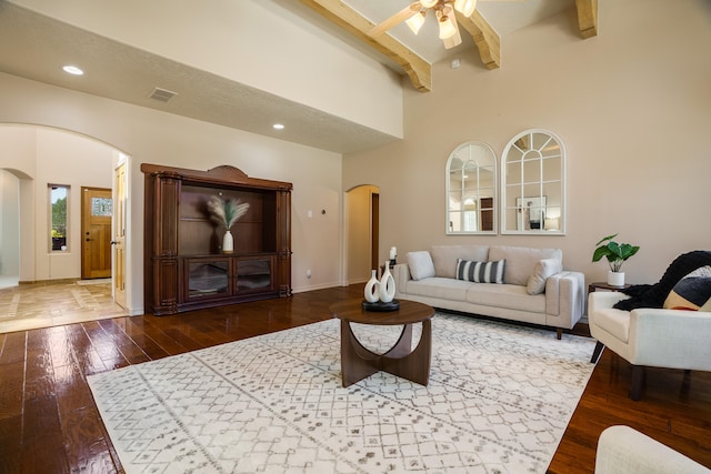 living room featuring a textured ceiling, ceiling fan, beam ceiling, and dark hardwood / wood-style flooring