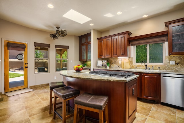 kitchen with a skylight, appliances with stainless steel finishes, a wealth of natural light, and a center island