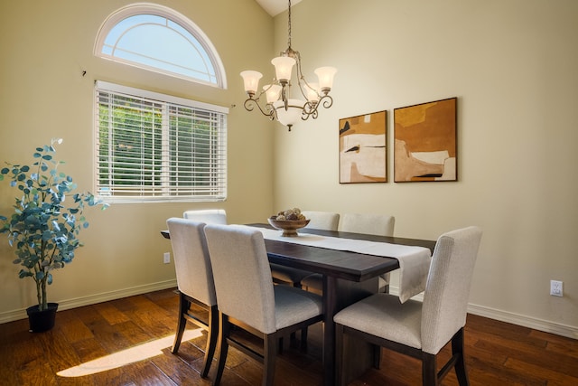 dining space with dark hardwood / wood-style flooring, a notable chandelier, and a towering ceiling