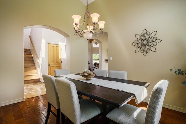 dining area featuring dark wood-type flooring, an inviting chandelier, and a towering ceiling