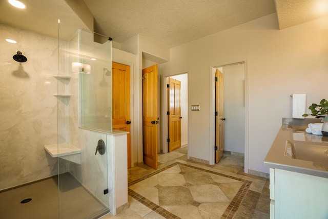 bathroom with vanity, a textured ceiling, a shower, and tile patterned floors