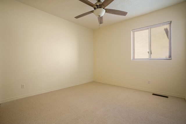 spare room featuring light colored carpet, ceiling fan, and a textured ceiling