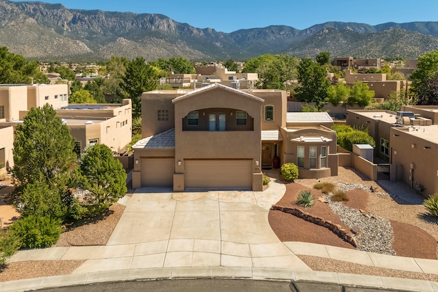 pueblo-style house with a garage and a mountain view