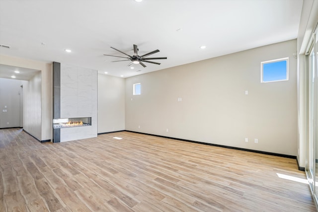 unfurnished living room featuring light hardwood / wood-style floors, ceiling fan, and a tile fireplace