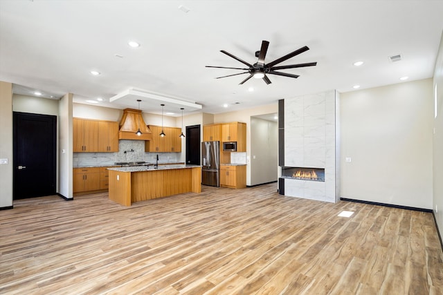 kitchen featuring a kitchen island with sink, light wood-type flooring, and hanging light fixtures