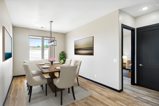 dining room featuring light wood-type flooring and a chandelier