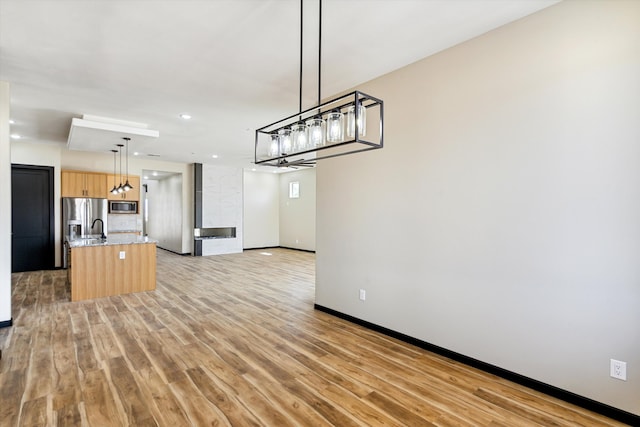 interior space featuring decorative light fixtures, light stone countertops, sink, and light hardwood / wood-style flooring