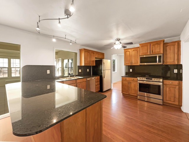 kitchen with sink, ceiling fan, decorative backsplash, appliances with stainless steel finishes, and hardwood / wood-style flooring