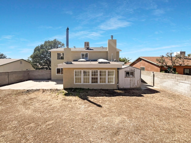 rear view of house featuring a storage unit and a patio