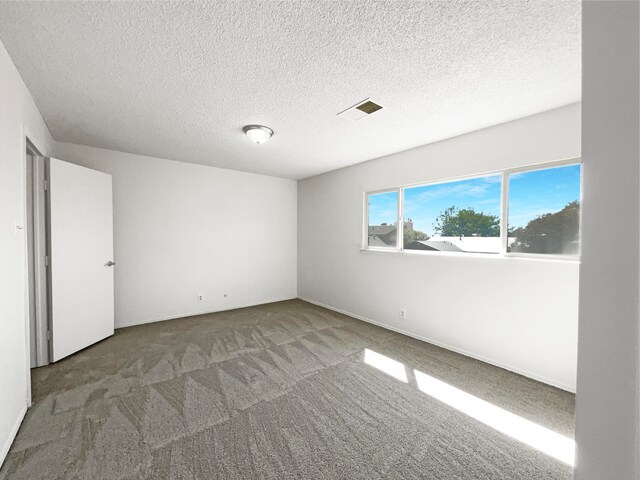 carpeted empty room featuring a textured ceiling