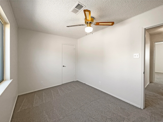 carpeted spare room with a textured ceiling and ceiling fan