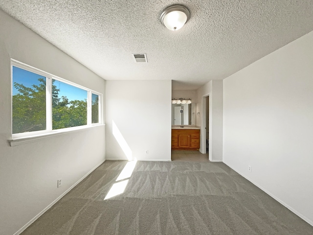 unfurnished bedroom featuring carpet, connected bathroom, and a textured ceiling