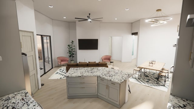 kitchen with ceiling fan with notable chandelier, light stone countertops, light hardwood / wood-style flooring, hanging light fixtures, and gray cabinets