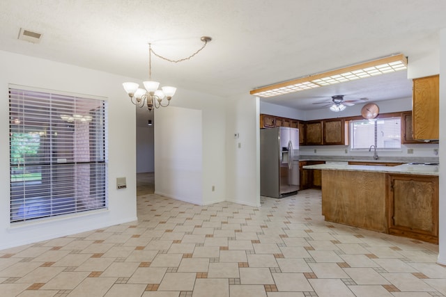 kitchen with sink, kitchen peninsula, decorative light fixtures, stainless steel fridge with ice dispenser, and ceiling fan with notable chandelier