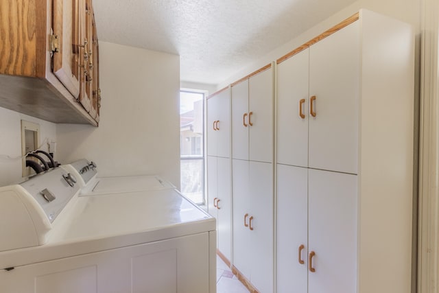 clothes washing area with cabinets, a textured ceiling, and independent washer and dryer