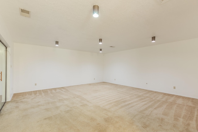 spare room with a textured ceiling and light colored carpet