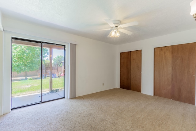 unfurnished bedroom with multiple closets, ceiling fan, access to exterior, and carpet flooring